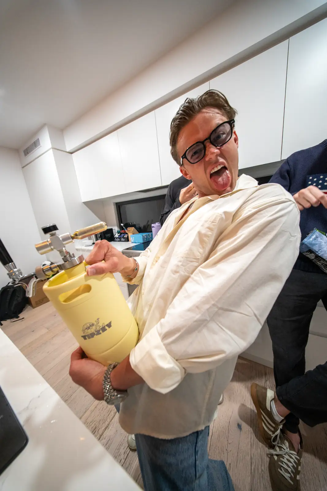 A man holding a pale yellow Tipzey mini keg in a kitchen