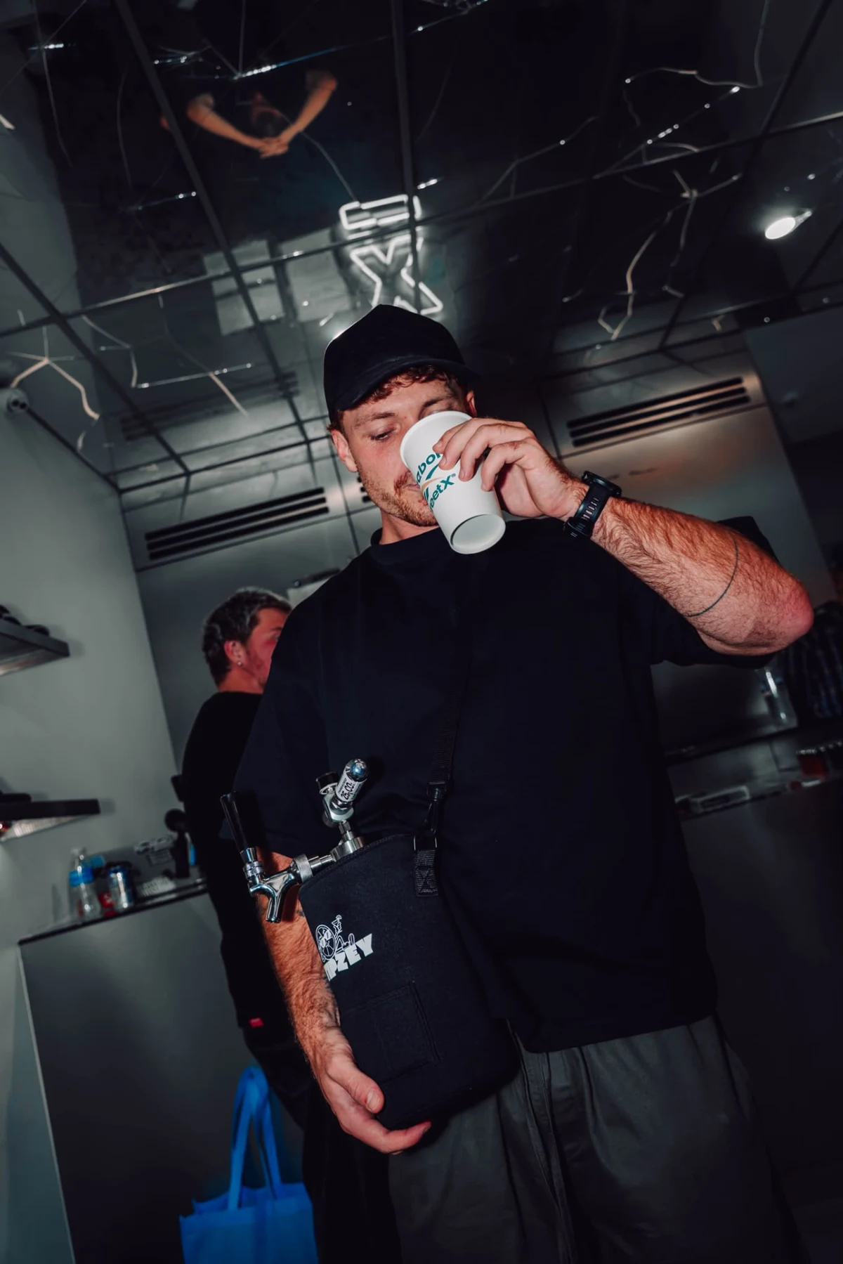 A customer enjoying a drink while holding a black Tipzey mini keg