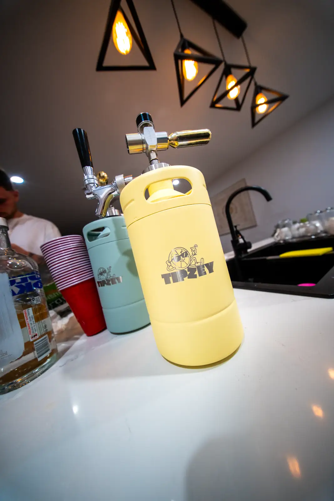 A pale yellow Tipzey mini keg with the tap fitted, on a kitchen counter